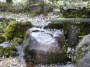 竹筒から流れ落ちる石神の湧水と手水鉢